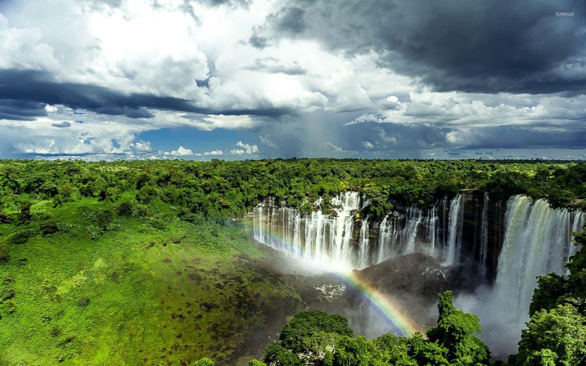 Kalandula Falls in Malanje under storm clouds with a rainbow